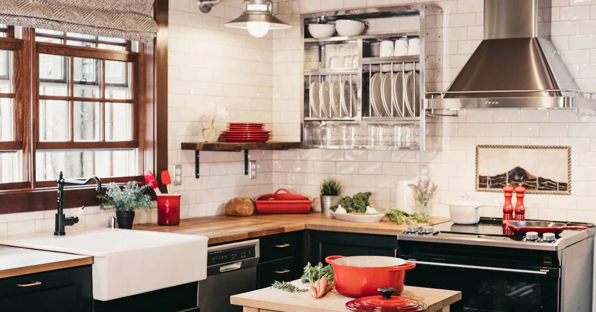 Moody dark cottagecore kitchen with forest-green cabinets, brass hardware, and copper pots