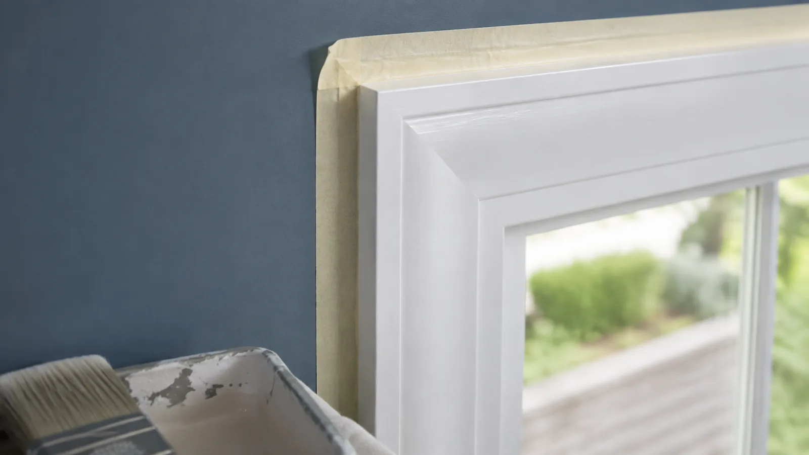 AI-generated illustration: Close-up white window casing with masking tape carefully pressed along its edge, adjacent muted blue wall, no active hand.